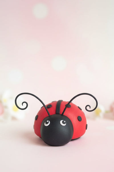Handcrafted red ladybug fondant cake topper figure with black dots and antennae
